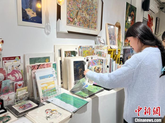 圖為藝術(shù)品商店內(nèi)，顧客挑選插畫(huà)作品?！＄婌?攝