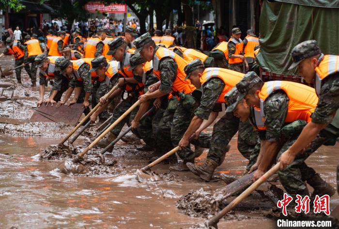 7月4日，萬(wàn)州區(qū)五橋街道，武警官兵清理街道上的淤泥。　冉孟軍 攝
