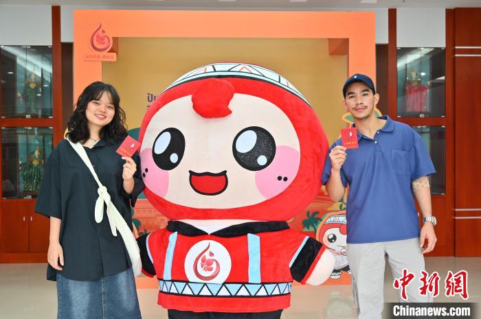 圖為泰國(guó)留學(xué)生手持獻(xiàn)血證與人偶合影?！∮峋?攝