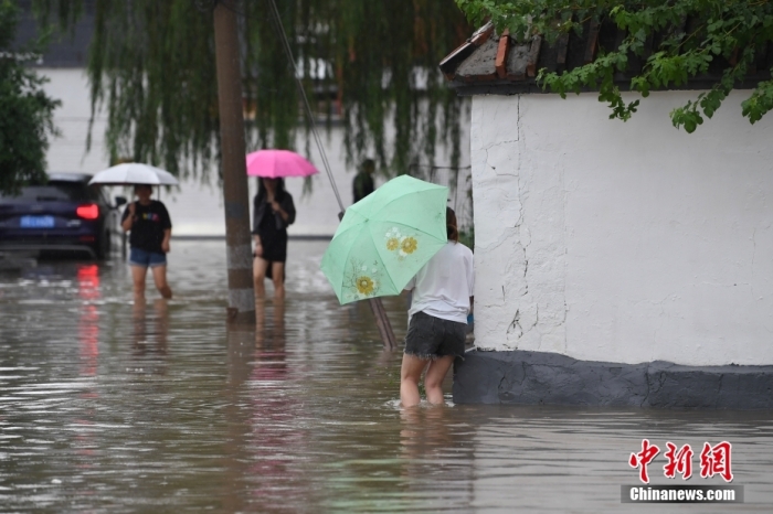 7月31日，市民行走在雨中的北京房山區(qū)瓦窯頭村。北京市氣象臺(tái)當(dāng)日10時(shí)發(fā)布分區(qū)域暴雨紅色預(yù)警信號(hào)。北京市水文總站發(fā)布洪水紅色預(yù)警，預(yù)計(jì)當(dāng)日12時(shí)至14時(shí)，房山區(qū)大石河流域?qū)⒊霈F(xiàn)紅色預(yù)警標(biāo)準(zhǔn)洪水。<a target='_blank' href='/'><p  align=