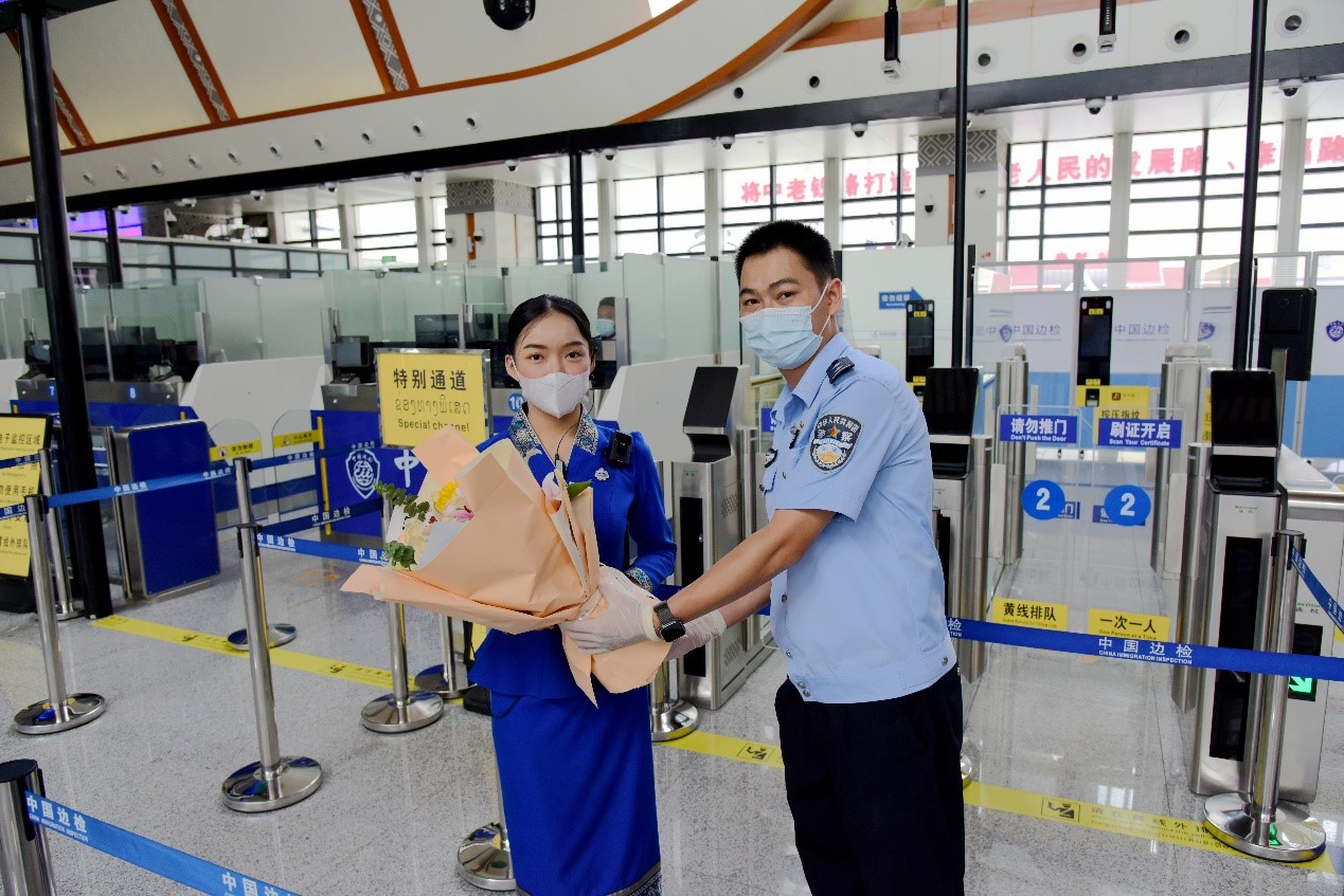 磨憨出入境邊防檢查站民警為中老鐵路第100萬(wàn)名出入境旅客，D888次國(guó)際旅客列車?yán)蠐爰藙?wù)員森達(dá)拉·妮緹婭（Sengdala Nitiya），送上鮮花。黃遠(yuǎn)飛 攝