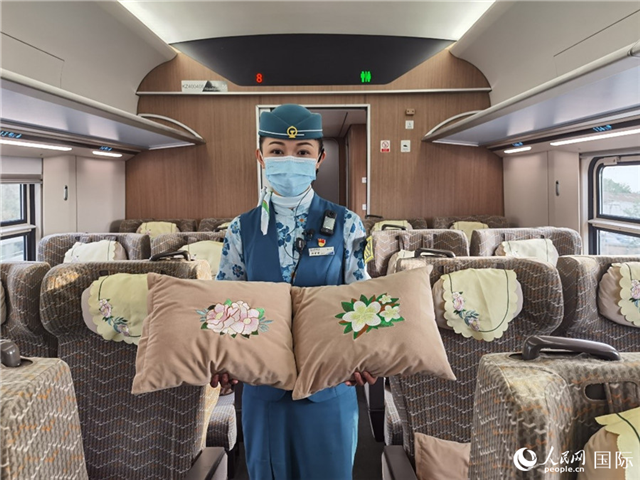 趙瑩靜展示中老鐵路國際旅客列車?yán)飵в兄袊档せê屠蠐胝及突ù汤C圖案的靠墊。人民網(wǎng)記者 杜明明攝
