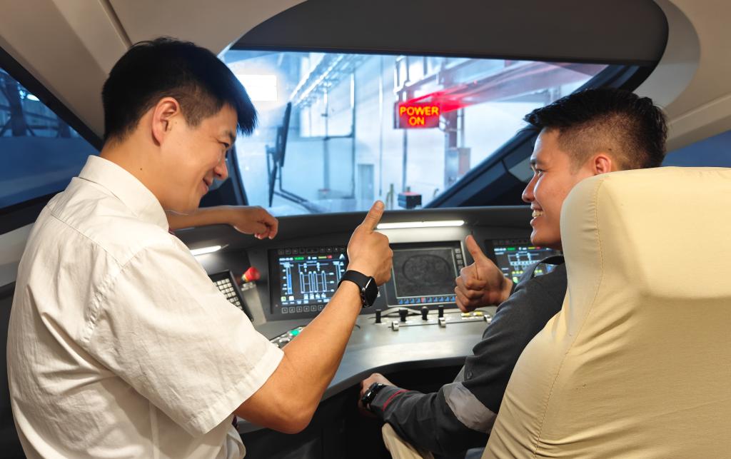8月25日，在印度尼西亞萬隆的雅萬高鐵德卡魯爾動(dòng)車所內(nèi)，中國(guó)師傅穆振（左）在向印尼火車司機(jī)塞蒂亞萬講解動(dòng)車組出庫前的上電作業(yè)。