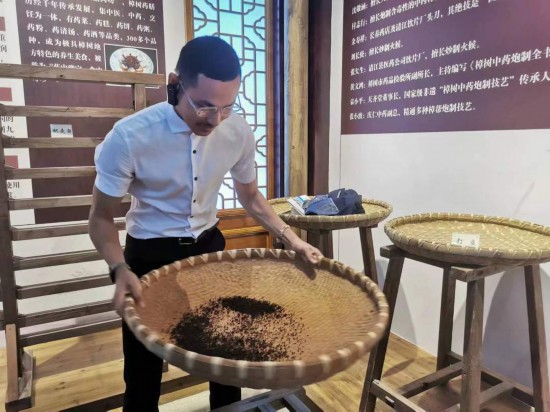 2023“一帶一路”媒體合作論壇聯(lián)合采訪團團員在非遺文化展示館體驗中藥炮制技藝。（本報記者 黃超攝）