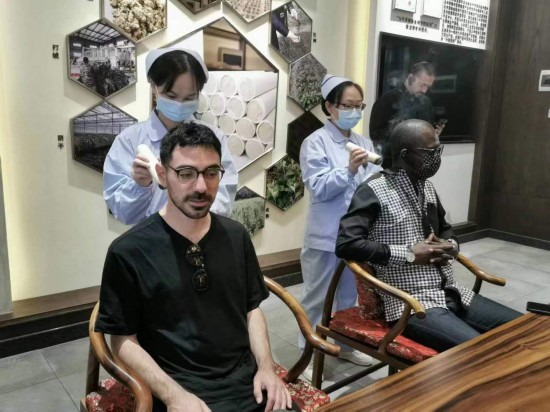 2023“一帶一路”媒體合作論壇聯(lián)合采訪團團員在九牛草展示館體驗艾灸。（本報記者 黃超攝）