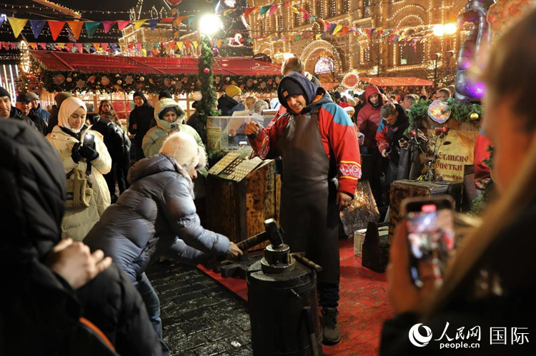 游客在新年集市上體驗制作紀(jì)念幣。人民網(wǎng)記者 隋鑫攝