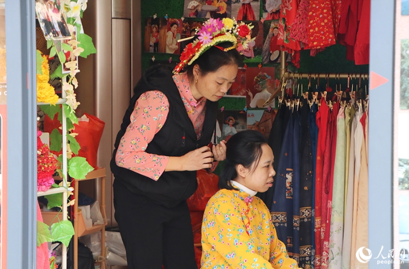 泉州府文廟附近，一名店主正為過(guò)路游客梳理頭發(fā)以佩戴“簪花圍”。人民網(wǎng) 黃東儀攝