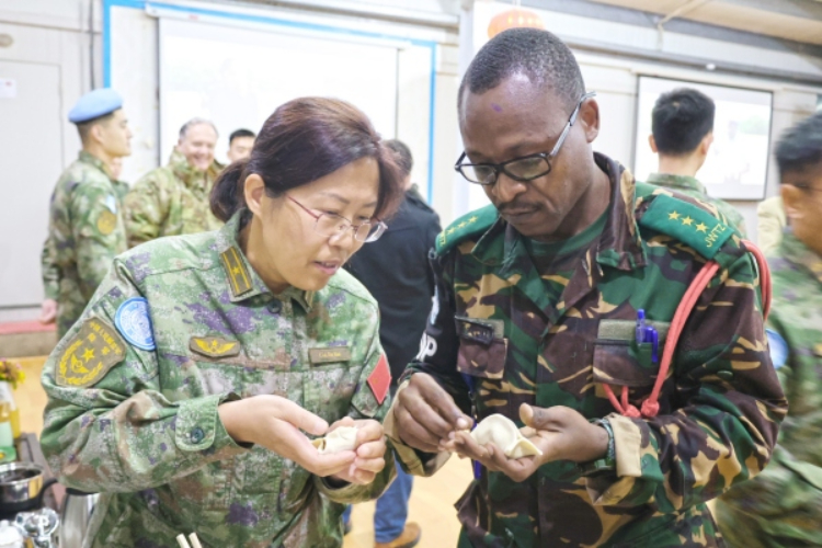 圖為維和官兵與外軍人員共同包餃子。胡光明攝