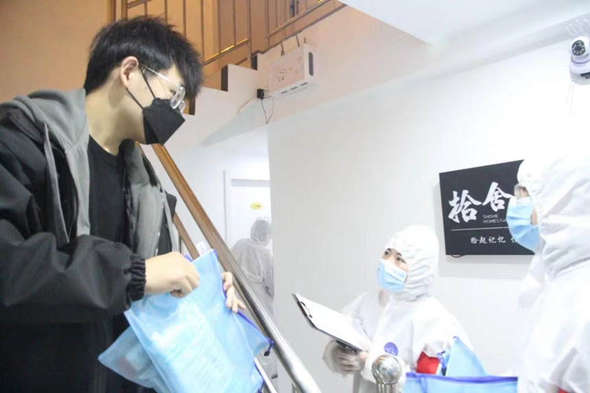 社區(qū)工作人員和志愿者身穿防護(hù)服上門送馬應(yīng)龍大健康防疫包。徐帥攝