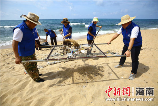環(huán)保志愿者用篩網“淘”出海灘上的垃圾。