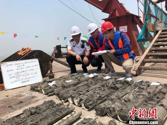 圖為勘察設(shè)計(jì)人員與海事局工作人員查看巖芯情況。　魏震 攝
