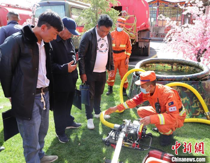 圖為森林消防員為護(hù)林員講解滅火裝備的使用方法?！〔际猩窒乐ш?duì) 供圖