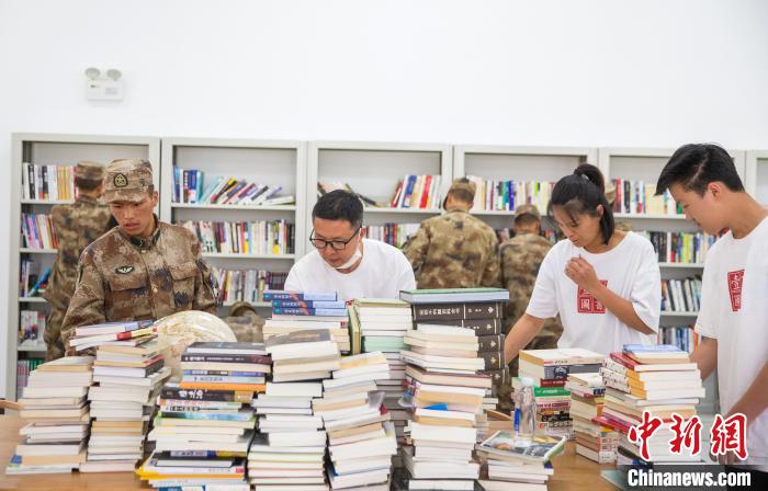 圖為志愿者們和邊防戰(zhàn)士整理圖書?！詵| 攝