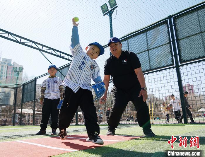 圖為來自臺灣的棒球教練劉興鴻(右)指導(dǎo)小棒球手?jǐn)S球技術(shù)?！●R銘言 攝