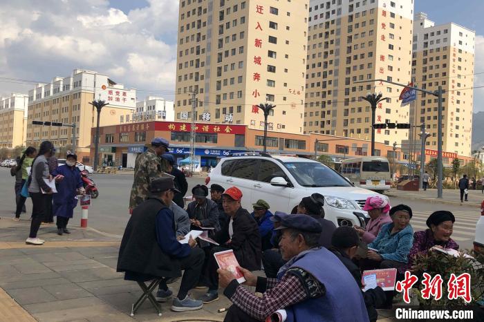 圖為會澤縣城易地扶貧搬遷安置點內(nèi)，老人們聚在廣場上聊天，身后是他們的新家。　繆超 攝