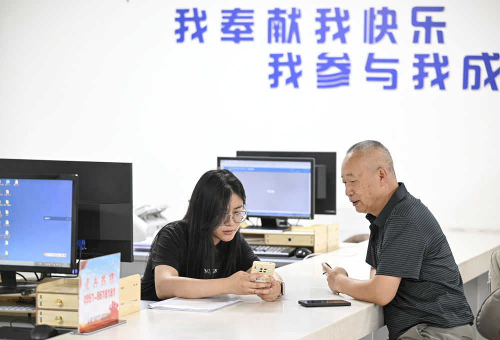 2024年6月20日，在寧夏銀川市金鳳區(qū)長(zhǎng)城花園社區(qū)黨群服務(wù)中心，工作人員幫助居民辦理業(yè)務(wù)。圖片來(lái)源 新華社