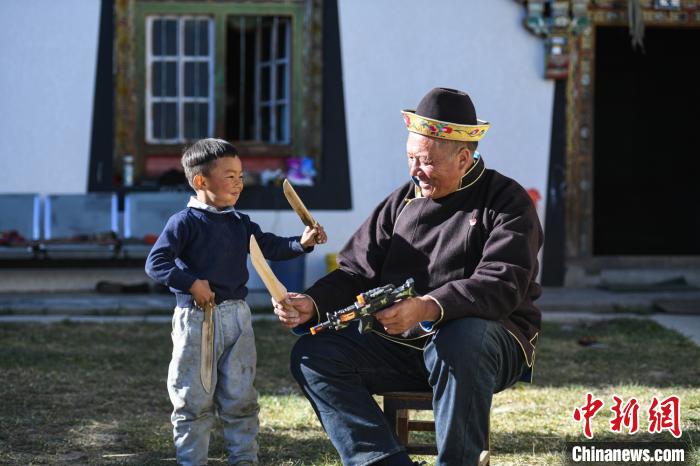 圖為米林縣扎西繞登鄉(xiāng)彩門(mén)村64歲的洛桑帶著孫子巴桑在院子的草地上玩耍。　何蓬磊 攝