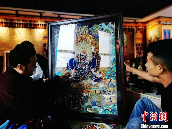 圖為久美尖措(左)與徒弟們展示唐卡作品?！?zhí)砀?攝