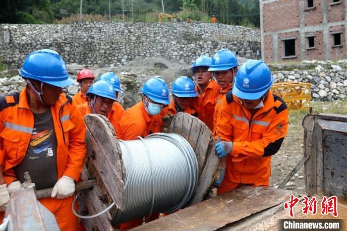 國網(wǎng)四川送變電公司搶險隊員將重達370公斤的鋼絞線搬上車。　劉湘釩 攝