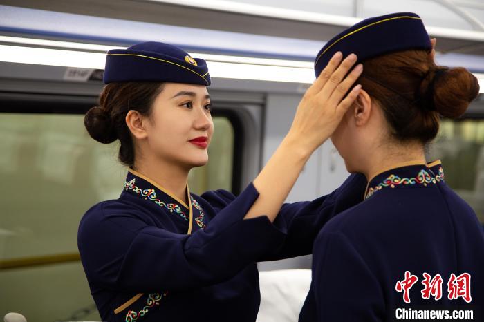 圖為青藏鐵路西格段“復(fù)興號(hào)”動(dòng)車組乘務(wù)員互相整理新制服?！±罾?攝