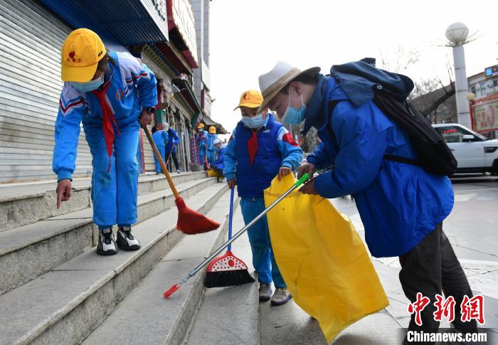 圖為拉薩市小學(xué)生打掃街道?！∝暩聛?lái)松 攝