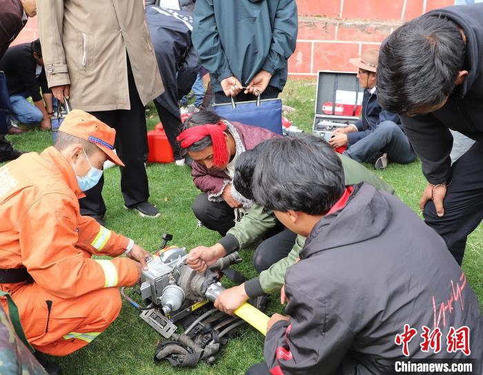 圖為森林消防員為護(hù)林員講解滅火裝備的使用方法?！〔际猩窒乐ш?duì) 供圖