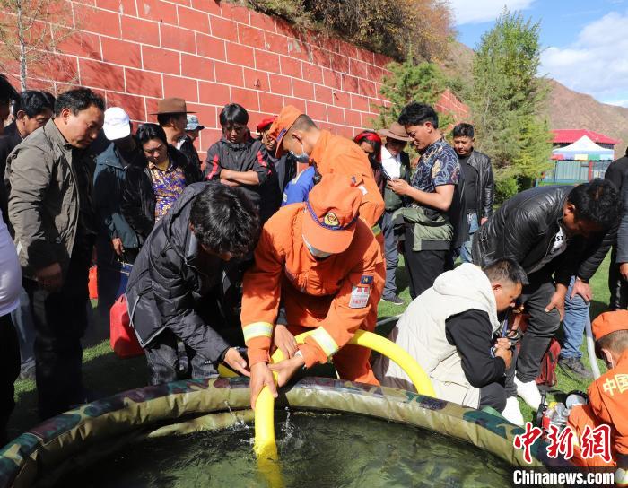 圖為森林消防員為護(hù)林員講解滅火裝備的使用方法?！〔际猩窒乐ш?duì) 供圖