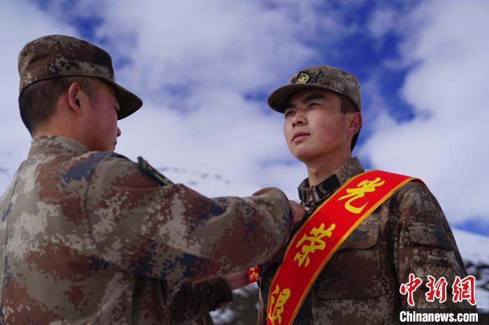 排長王朝偉(圖左)給退伍老兵佩戴大紅花?！∥鞑厣侥宪姺謪^(qū)某團(tuán)供圖