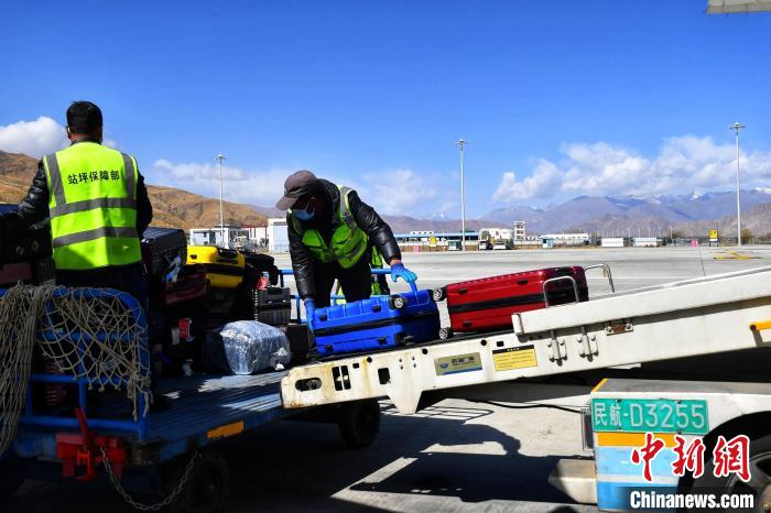 圖為機場工作人員傳送旅客行李箱?！≈芎?攝