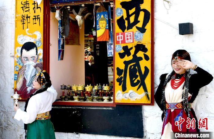 4月17日，游客身著藏式元素服裝在拉薩八廓街拍照留念。　李林 攝
